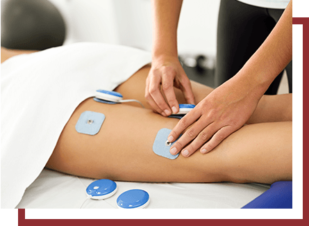 A chiropractor applying electric stimulation therapy patches to a patient's legs