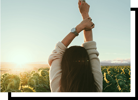 Woman stretching her arms up in a sunflower field